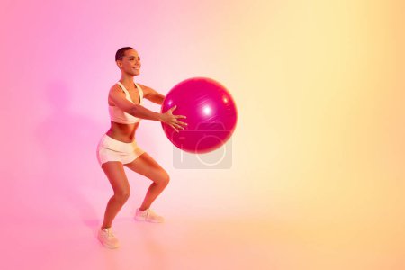 Photo for A young woman in sportswear performs a graceful yoga pose, showcasing tranquility and balance against a soft pink and yellow gradient backdrop. Sport, fitness and weight loss - Royalty Free Image