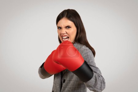 Foto de Empresaria decidida en traje con guantes de boxeo, mostrando expresión feroz y postura de lucha, simbolizando desafíos empresariales - Imagen libre de derechos