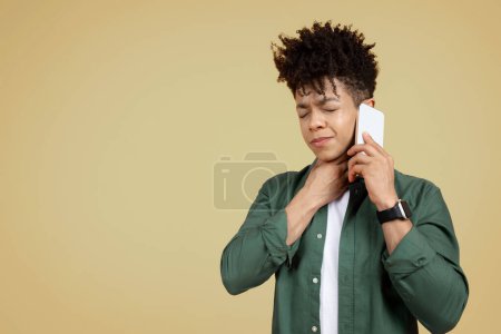 Young sad ill sick black man talk speak on mobile cell phone with doctor, isolated on beige background studio portrait, copy space. Healthy lifestyle disease virus treatment cold season recovery