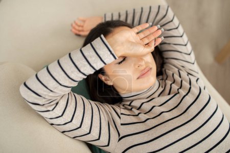 Photo for Tired sad young caucasian woman sleep with closed eyes on sofa in living room interior, top view. Free time, rest, relax, break and lifestyle at home, overwork and insomnia - Royalty Free Image