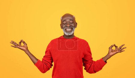 Photo for Blissful senior african american man with a white beard, eyes closed and hands in a yoga mudra, wearing a red sweater on a yellow background, embodying calmness and serenity - Royalty Free Image