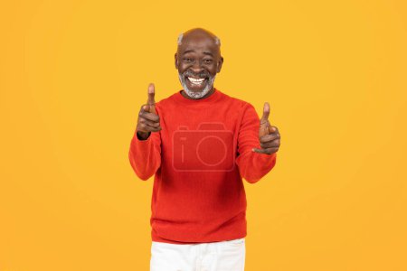 Happy senior african american man coach point finger at camera, motivated, isolated on yellow background, conveying friendliness and openness. Youre turn, choose, win gesture