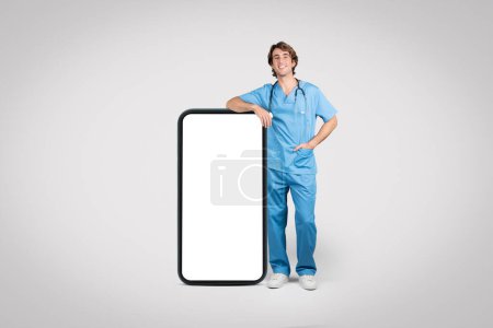 Smiling male nurse in scrubs leaning on giant smartphone, representing the bridge between healthcare providers and digital health technology