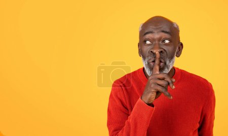 Geheimnisvoller älterer schwarzer Mann mit weißem Bart, der in einer schrillen Geste den Finger an seine Lippen legt und einen leuchtend roten Pullover vor einem schlichten gelben Hintergrund trägt, der Stille suggeriert