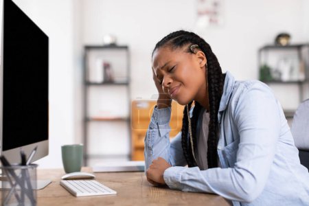 Foto de Agotado negro adolescente señora descansando la cabeza en la mano, sintiéndose fatigado y abrumado mientras se sienta en su escritorio con la computadora, indicativo de burnout estudio - Imagen libre de derechos