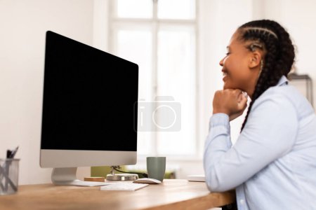 Téléchargez les photos : Étudiante noire engagée profondément concentrée en regardant un écran d'ordinateur vierge, peut-être en apprenant ou en réfléchissant sur un projet, une maquette - en image libre de droit