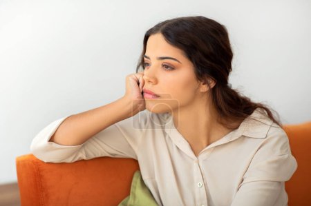 Photo for Portrait Of Pensive Upset Young Woman Sitting On Couch At Home, Depressed Beautiful Female Leaning Head On Hand And Looking Away, Suffering Life Problems Or Seasonal Depression, Closeup Shot - Royalty Free Image