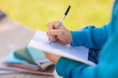 Photo for Closeup of notebook in student guys hands as he writing and taking notes, doing his college homework outdoors at campus park, cropped shot of unrecognizable learner with his workbook - Royalty Free Image