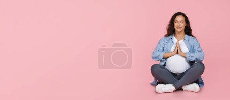 Téléchargez les photos : Jeune femme enceinte méditant sur fond de studio rose, dame expetcante assise en position lotus avec les mains jointes, pratiquant le yoga pour une grossesse en bonne santé, panorama avec espace libre - en image libre de droit