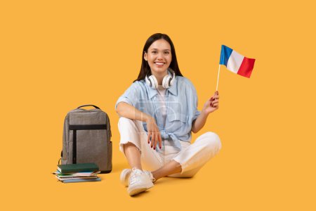 Téléchargez les photos : Étudiante joyeuse arbore fièrement le drapeau français, symbolisant son lien avec l'éducation mondiale et l'échange culturel, mode de vie académique technico-averti - en image libre de droit