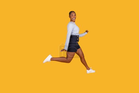 Photo for Happy young african american woman leaping in the air isolated on yellow studio background. Joyful black lady in summer clothing enjoying life, have good mood, copy space - Royalty Free Image