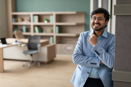 Photo for Career Achievement. Happy successful Middle Eastern businessman standing in modern office interior, smiling to camera, showcasing happiness and confidence over corporate growth - Royalty Free Image