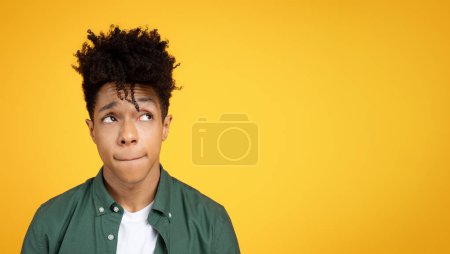 Photo for Confused stylish handsome millennial african american guy looking at blank copy space mockup for advertisement, grimacing, isolated on yellow background, panorama - Royalty Free Image