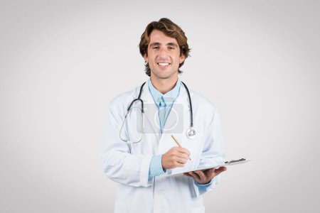 Photo for Confident and approachable male doctor holding clipboard, ready to take patient notes, representing the blend of care and expertise in modern medicine - Royalty Free Image