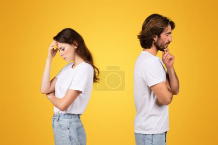 Photo for Upset caucasian woman with a hand on her forehead in frustration and pensive man with hand on chin looking away from each other, in white shirts on a yellow background, studio - Royalty Free Image