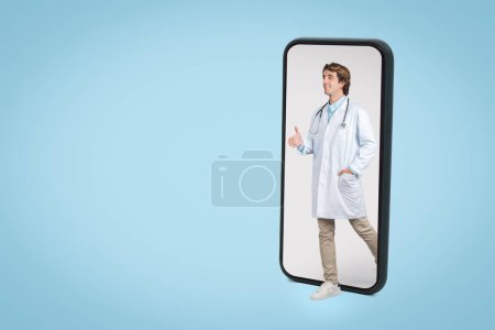Photo for Confident young man doctor wearing stethoscope and white coat appears to stand inside mobile phone screen, representing modern telehealth services - Royalty Free Image