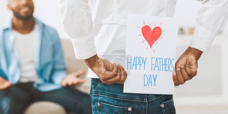 Foto de Daudghter saludo papá con el Día de los Padres, niña oculta tarjeta de felicitación para el padre detrás de la espalda - Imagen libre de derechos