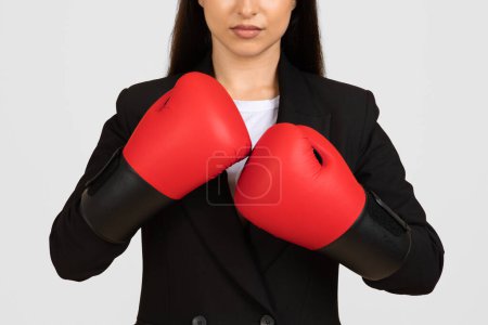Foto de Empresaria enfocada con traje muestra disposición y determinación con guantes de boxeo rojo, simbolizando la fuerza en los negocios, recortado - Imagen libre de derechos