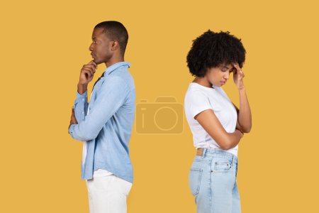 Téléchargez les photos : Un jeune homme noir contemplatif et une jeune femme frustrée à la fois profondément dans la pensée, face à l'autre sur un fond jaune uni. Problèmes relationnels, querelle - en image libre de droit