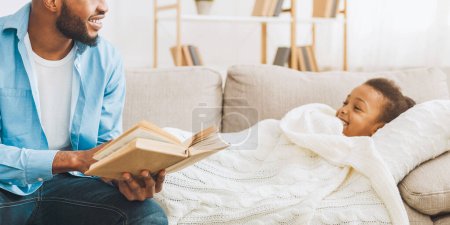 Téléchargez les photos : Père attentionné lisant des histoires à sa petite fille avant de se coucher à la maison, espace vide - en image libre de droit