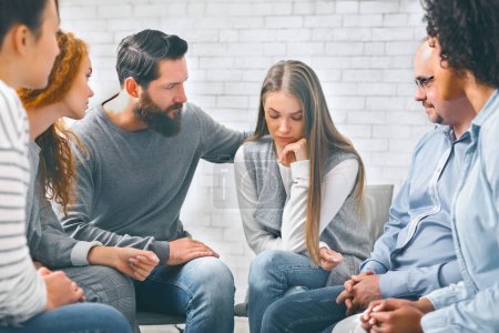 Concerned patients comforting depressed woman in rehab group at therapy session