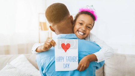 Photo for Little girl hugging dad and giving him postcard, congratulating with fathers day - Royalty Free Image