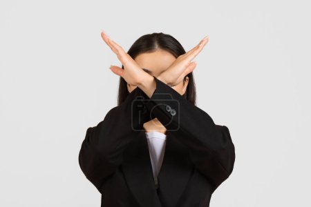 Téléchargez les photos : Jeune femme d'affaires professionnelle en costume noir faisant signe timeout geste avec ses mains sur son visage, debout sur fond de studio gris - en image libre de droit