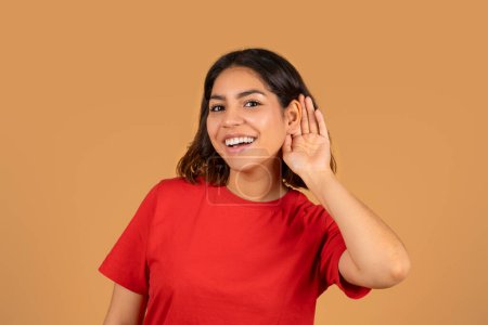 Photo for Curious excited young arabic woman touching her ear with hand and looking at camera, listening to rumor, gossip, interesting news, isolated on beige studio background - Royalty Free Image