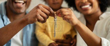 Photo for Mortgage, house buying concept. Cropped of african american family father, mother and little daughter holding key form new home, selective focus on hands, web-banner - Royalty Free Image