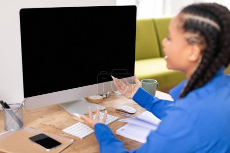 Perplexed black female student with braids gestures questioningly at blank computer screen, indicating confusion or a problem during online lesson at home
