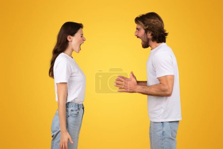 Intensa pareja de jóvenes europeos en camisetas blancas que participan en un desacuerdo verbal o una conversación animada, uno frente al otro con la boca abierta, sobre un fondo amarillo brillante