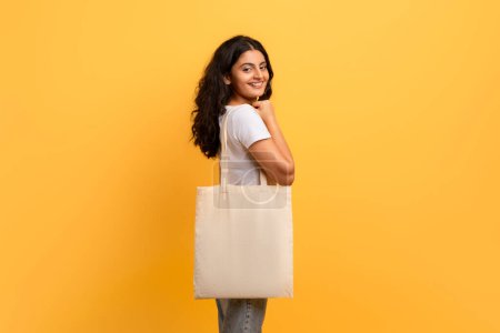 A woman turns back holding an eco-friendly tote bag, embodying sustainable shopping and fashion