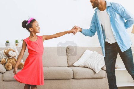 Téléchargez les photos : Petite fille dansant avec son père, s'amusant à la maison - en image libre de droit