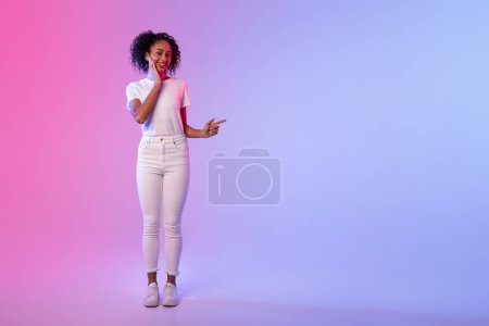 Fröhliche Frau in lässiger Kleidung gestikuliert mit der Hand vor zweifarbigem neonfarbenem Hintergrund