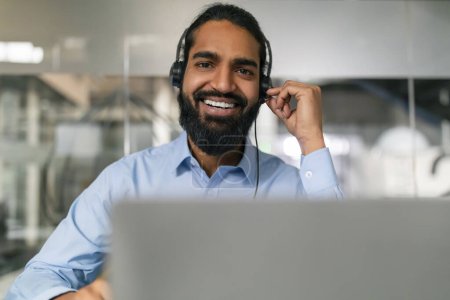 Selbstbewusster Geschäftsmann mit einladendem Lächeln, der sein drahtloses Headset auf ein virtuelles Meeting vorbereitet