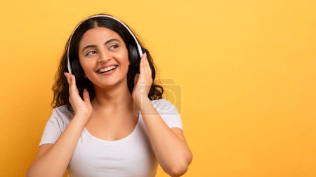Eine fröhliche junge Frau mit Kopfhörern genießt ihre Lieblingsmusik und veranschaulicht Freizeit und Entspannung