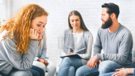 Foto de Mujer pelirroja molesta sentada en la sesión de terapia de grupo, pensando en sus problemas, espacio vacío - Imagen libre de derechos