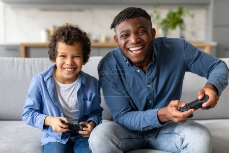Joyful father and son have fun playing video games together in a cozy living room