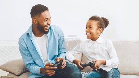 Happy father and daughter playing video game, spending time together at home