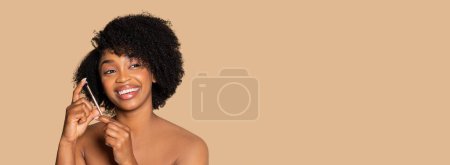 Téléchargez les photos : Jolie femme noire mettant en valeur son teint impeccable et ses cheveux bouclés, évoquant beauté et bonheur sur ton beige, espace libre, panorama - en image libre de droit