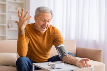 Foto de Un anciano parece divertirse midiendo su presión arterial con un monitor digital, sugiriendo conciencia de salud - Imagen libre de derechos