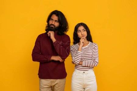 The man and woman both exhibit contemplative expressions, posing in a thought-provoking stance on a yellow backdrop