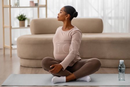 Téléchargez les photos : Femme africaine américaine enceinte en bonne santé faisant de l'exercice sur un tapis de yoga à la maison, copiez l'espace. Dame noire future mère prenant soin de son corps et de sa santé, faisant du sport - en image libre de droit