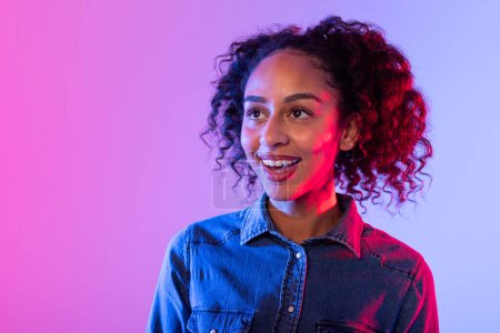 Confident young woman with a warm smile and casual denim jacket, neon-toned backdrop