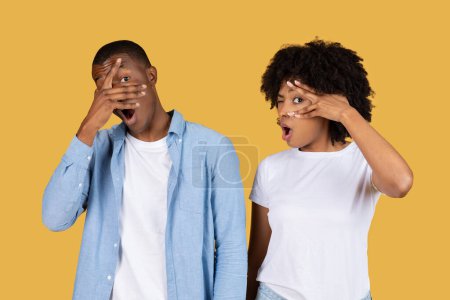 Photo for Astonished millennial African American man and woman with hands on their faces showing exaggerated expressions of surprise and shock, against a vivid yellow background, studio - Royalty Free Image