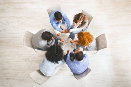 Groupe de personnes assises en cercle, dictant leurs problèmes pendant la séance de thérapie, vue du dessus
