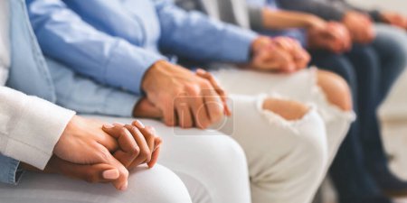 Photo for Group support. People holding hands, sitting in row, close up - Royalty Free Image