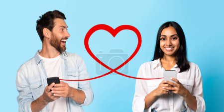 Téléchargez les photos : Un homme joyeux dans une veste en denim regarde avec excitation son téléphone tandis qu'une femme heureuse dans un chemisier blanc fait de même, tous deux reliés par une forme de coeur rouge sur un fond bleu clair - en image libre de droit