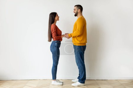 A man and woman stand side by side holding hands, featuring blurred face effect to evoke anonymity and uniformity in humans