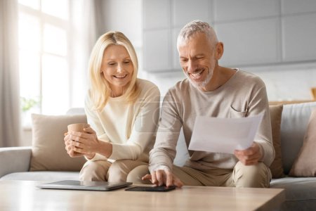 A joyful elderly couple engaged in reviewing financial documents while relaxing at home with cups of coffee